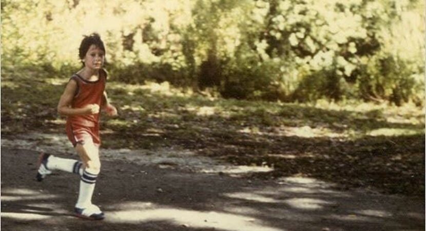 Jeune coureur en tenue vintage courant sur un chemin ombragé